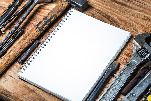 Various tools and the blank notebook on a wooden background