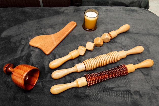 Various tools and rollers to apply wood therapy treatments on a gray velvet blanket