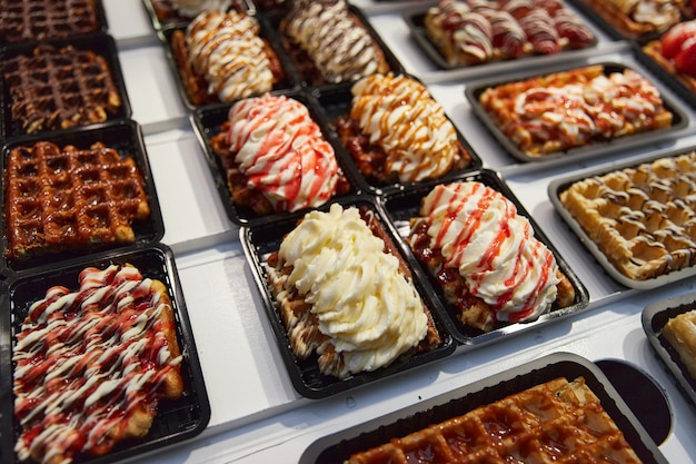 Various of traditional belgian waffles topped with chocolate speculoos whipped cream and fruit displ