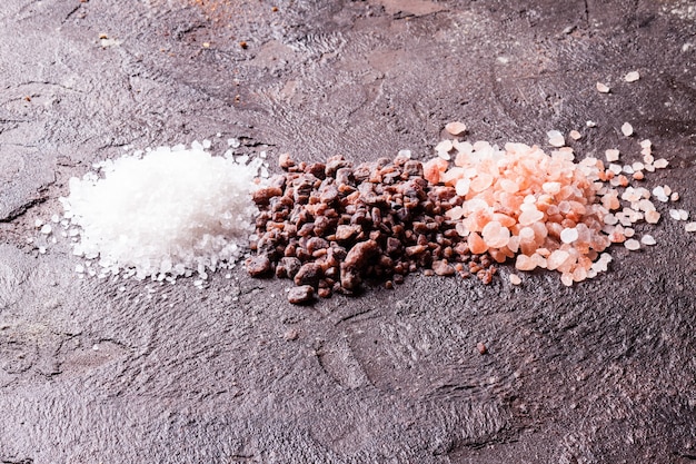 Various tupes of salts, pink Himalayas and black with sea salt on slate background