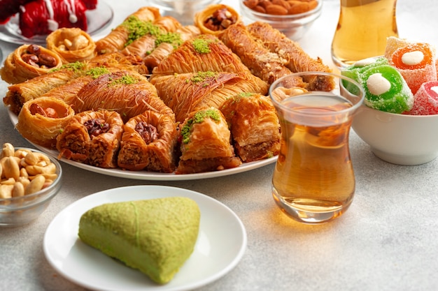 Various turkish sweets and cup of tea on white textured background