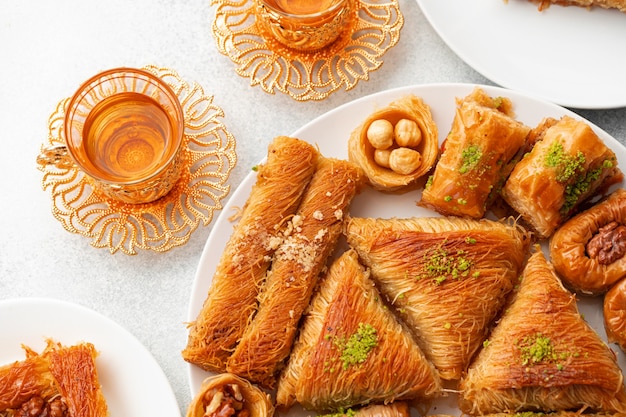 Various turkish sweets and cup of tea on white textured background