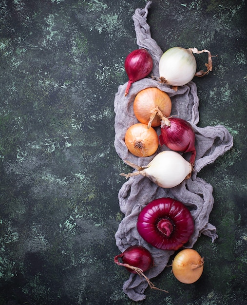 Various type of onions on green background. Top view