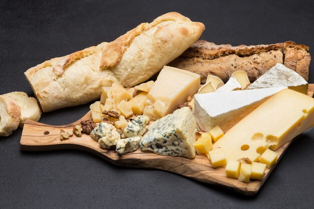 Various types of cheese and bread on wooden board