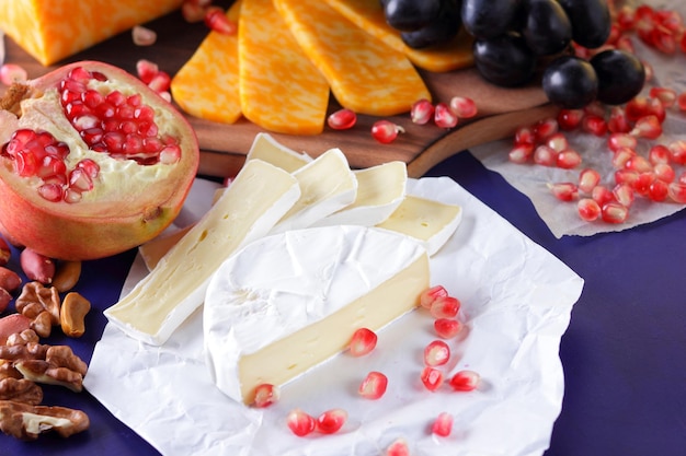 Various types of cheese composition on a blue background closeup Assorted cheeses fruits and nuts on a wooden board