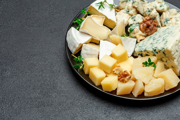 Various types of cheese in dark plate