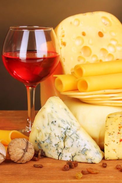 Various types of cheese on wooden table on brown background