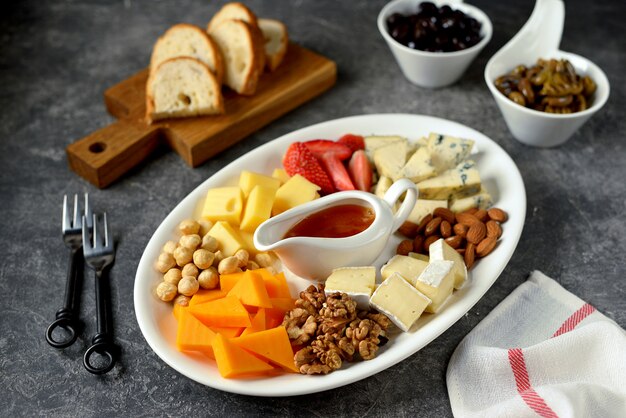 Различные виды сыров с оливками, орехами, фруктами и медом. Закуска для винной вечеринки.