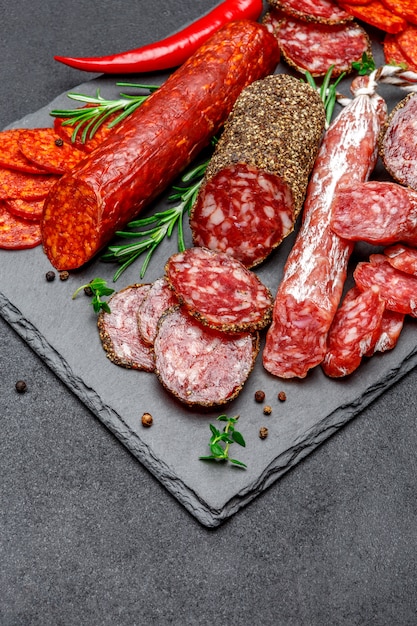 Various types of Dried organic salami sausage on stone serving board