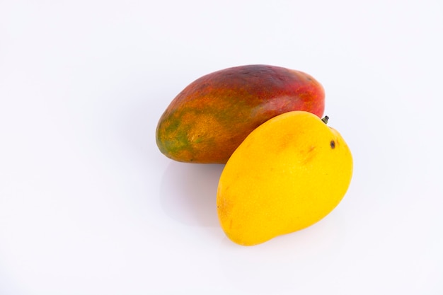 Various types of mango with yellow and red peel, on a white wall. Copy space.