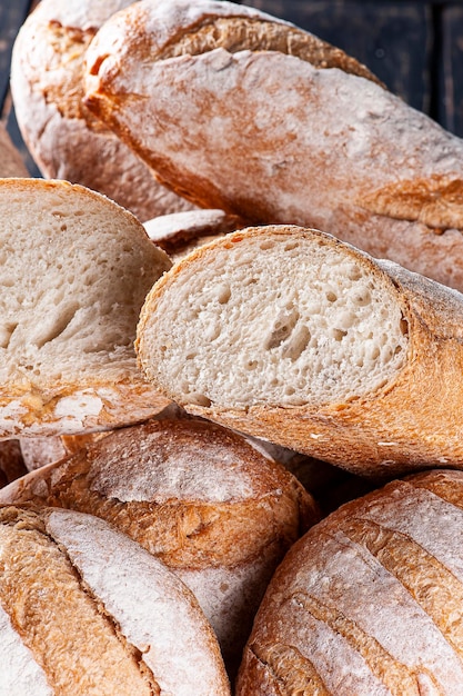 Foto vari tipi di pane a fermentazione naturale insieme in un cesto uno tagliato a metà per vederne l'interno