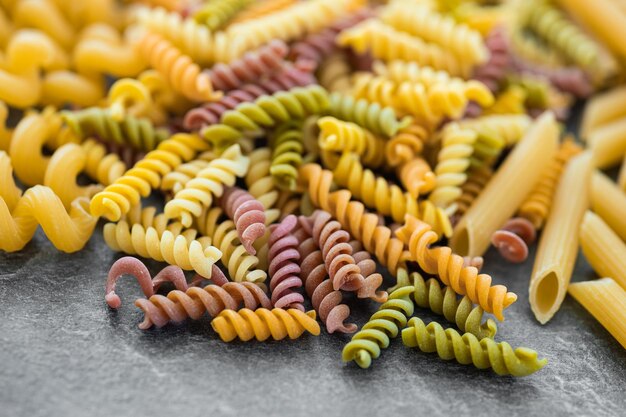 Various types of pasta on dark background from above