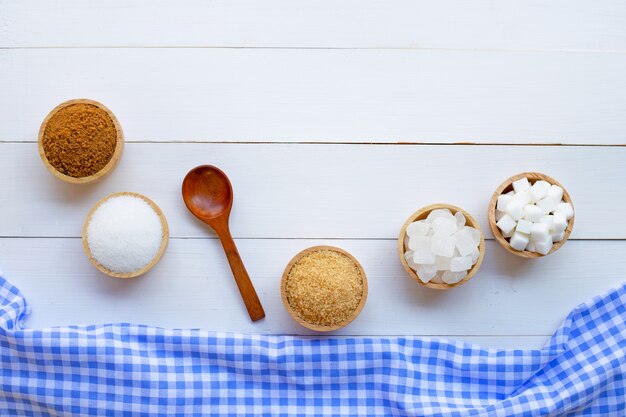 Various types of sugar on wooden background.