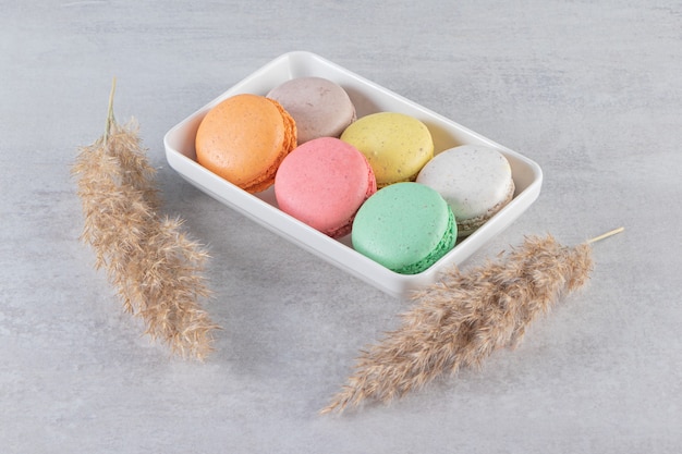 Various types of sweet almond cakes in white bowl on stone table. 