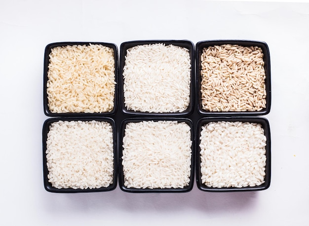 Various types of white and gray rice in black bowls on white