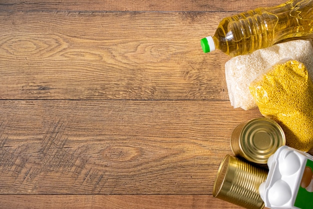 Various uncooked cereals, grains, oil and canned food on a wooden table. Ingredients for cooking.