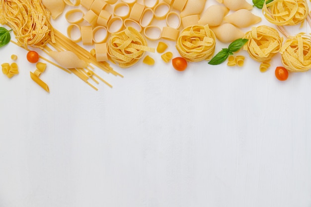 Various uncooked pasta on wooden background