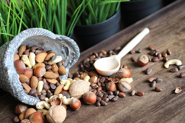 Photo various useful and tasty nuts on a wooden table and pots with green grass