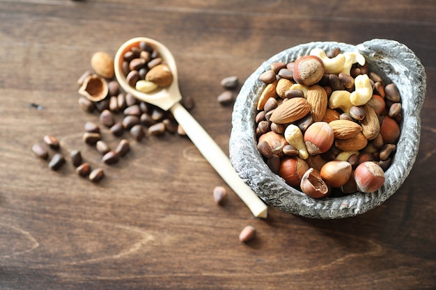 Various useful and tasty nuts on a wooden table and pots with green grass