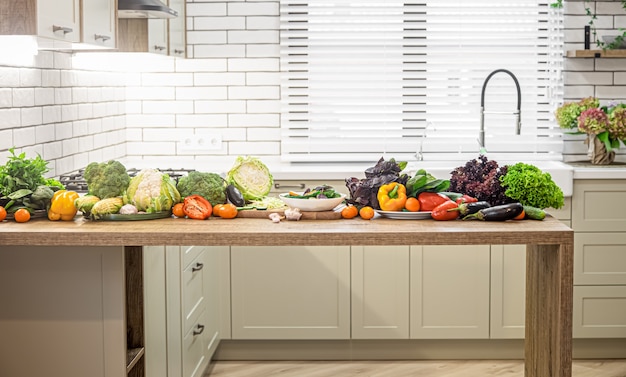 Various vegetables on a wooden table against the background of a modern kitchen interior.