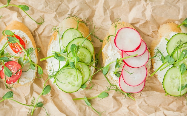 Различные вегетарианские бутерброды с овощами и зеленью на пергаменте на светлом столе. Правильное питание. Диетическое питание. Продовольственный фон. Вид сверху. Крупный план.