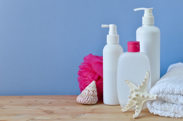 Various vessels for body care, a washcloth and a roll of towels with yellow small flowers on a light background on a wooden table.