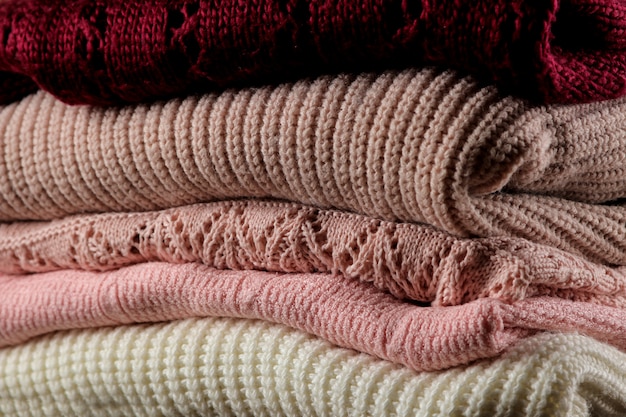 Photo various warm sweaters piled on a brown wooden background