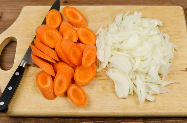 Variously sliced for cooking carrots and onions on a cutting board