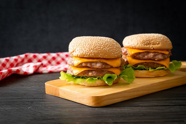 varkenshamburger of varkensburger met kaas op een houten bord