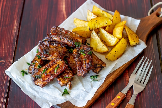 Varkensribbetjes met aardappelen op een houten tafel. Barbecue. Grill. Amerikaanse keuken. Recept.