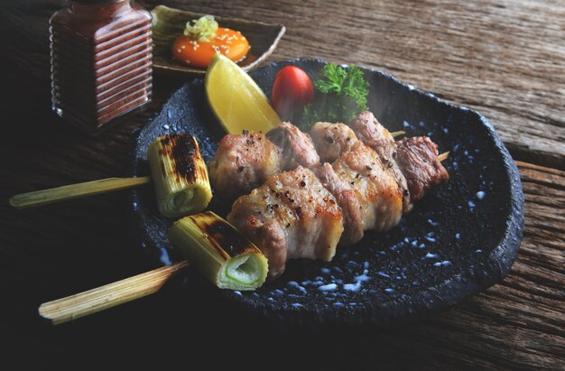 Varkensspiesjes in Japanse stijl, gegrild in de izakaya-bar, dienen met weinig licht en donkere schaduw.