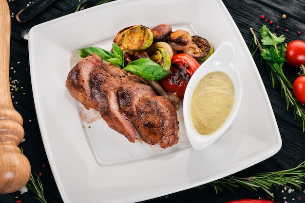 Varkenssteak met gegrilde groenten op een bord Op een houten ondergrond Bovenaanzicht Kopieer de ruimte