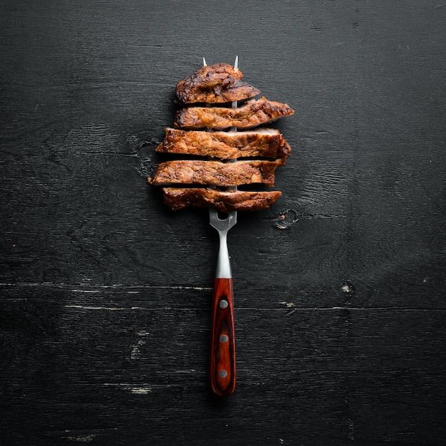 Varkenssteak op de vork Op een houten ondergrond Bovenaanzicht Vrije ruimte voor uw tekst