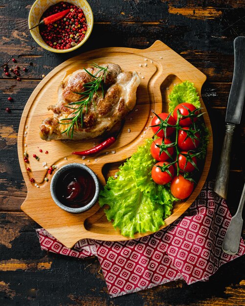 Varkenssteak op een houten bord met kerstomaatjes en salade rustieke gerechten