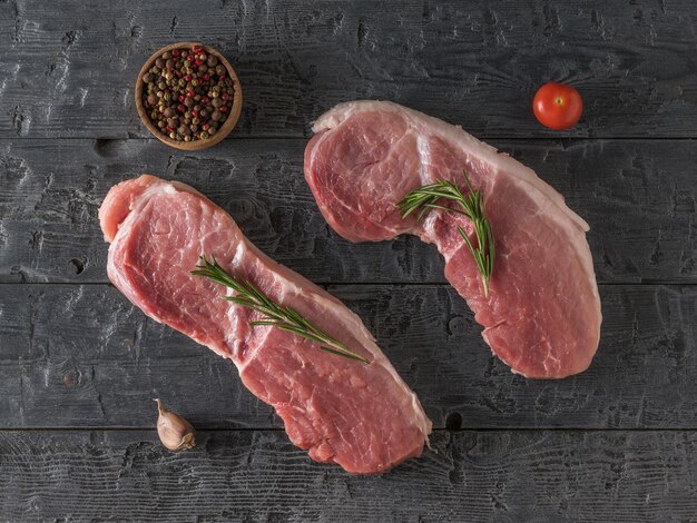 Varkensvlees in de vorm van steaks op een houten tafel. Ingrediënten voor het koken van vleesgerechten. Het uitzicht vanaf de top.