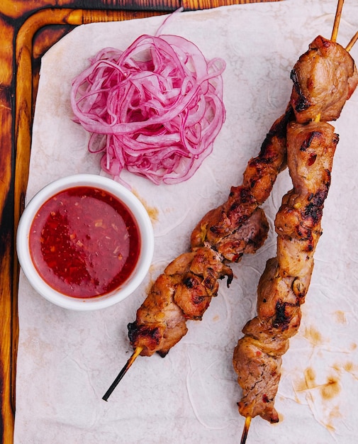 Foto varkensvlees kebab op een houten spies en rode ui