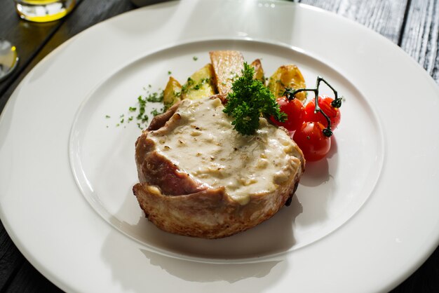 Varkensvlees met witte champignonsaus gegarneerd met gebakken aardappelen en cherry tomaten.