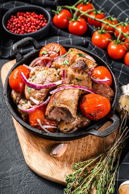 Varkensvlees Shish kebab met ui en tomaat in de pan. Gegrilld vlees. Zwarte achtergrond. Bovenaanzicht.