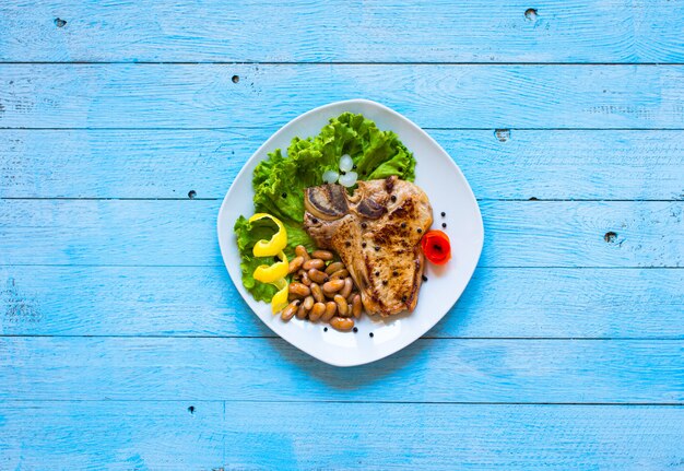 Varkensvlees steak zelfgemaakt koken met kruiden verlaat sla op houten snijplank, en een schotel,