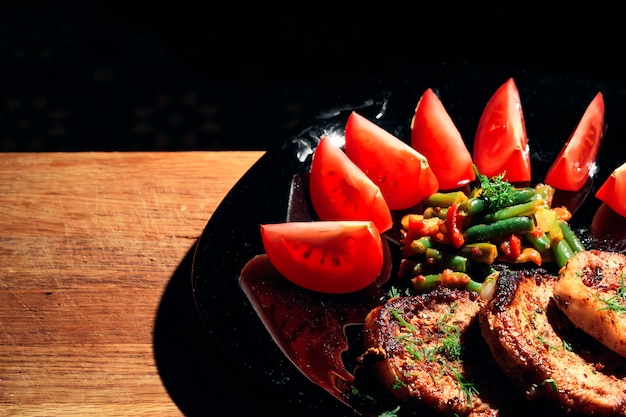 Varkensvleeslapje vlees op een zwarte plaat met groenten