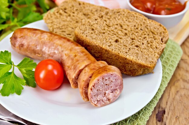 Varkensworsten gegrild in de plaat op een servet, brood, saus, tomaat, peterselie op een houten planken achtergrond