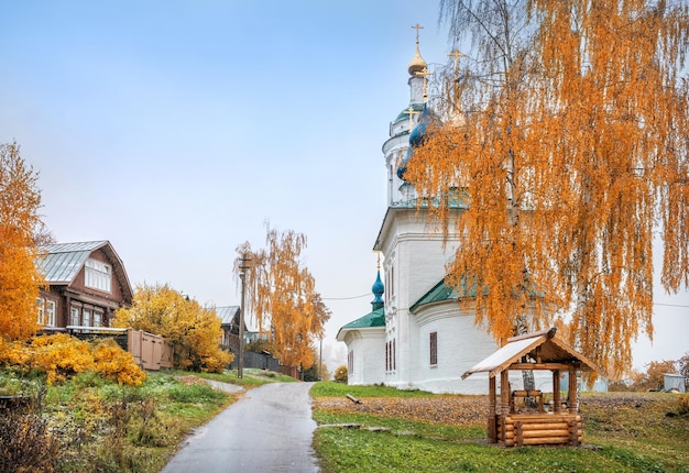 Церковь Варвары в Плесе и деревянный колодец рядом с красной осенней березой