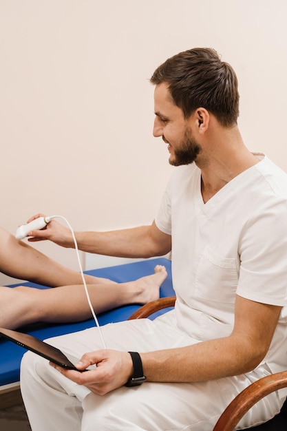 Vascular surgeon examines arteries and veins of legs using portable ultrasound machine Leg ultrasound examination before surgery