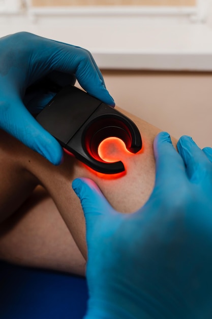 Vascular surgeon examines leg veins of woman using led venous scanner with red illumination Venous led scanner for helping to locate the veins