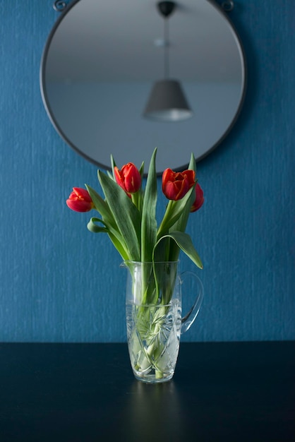 A vase of flowers at the blue wall in the room