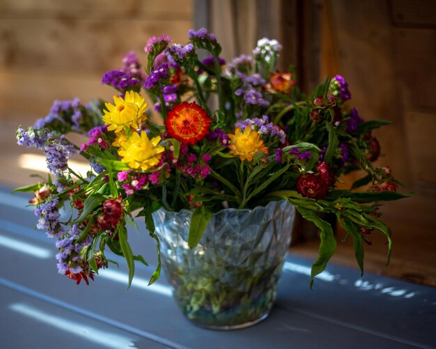 Photo a vase of flowers is on a blue table with a wooden fence in the background.