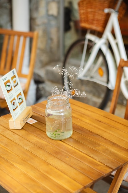 A vase of flowers on a table in a cafe outside