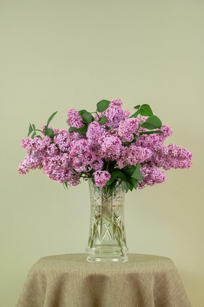 A vase of lilacs is on a round table.