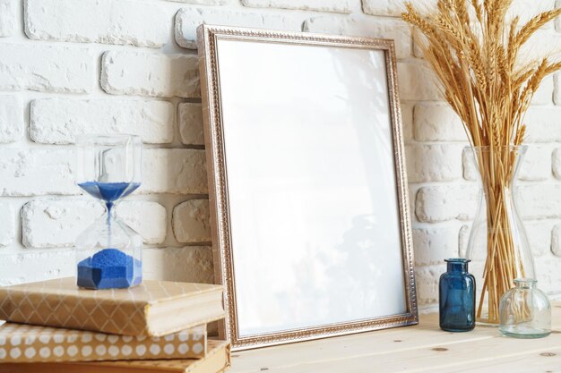 Vase met tarweoren en fotoramens tegen een bakstenen muur