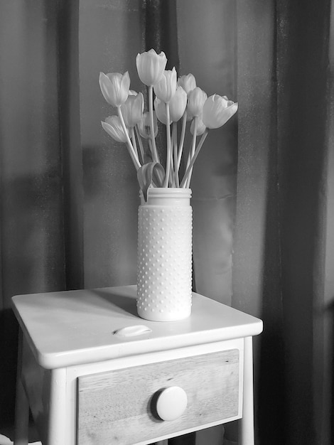 Фото Ваза с тюльпанами на столе дома черно-белая фотография